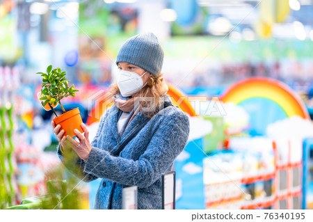buying plants in a flowerpot in the garden center 76340195