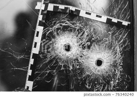 bullet holes in a glass shop window marked with a police tape bullet holes in a glass shop window marked with a police tape 76340240