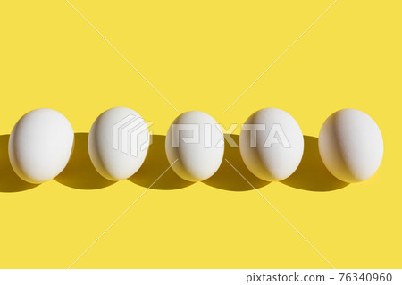 White fresh eggs in line on yellow background. White fresh eggs in line on yellow background. 76340960