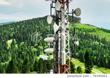 Telecommunication transmitter tower with antennas of cellular communication in mountains against sky and clouds Telecommunication transmitter tower with antennas of cellular communication in mountains against sky and clouds 76340981