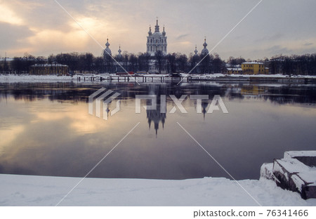 St. Petersburg cityscape with Smol'nyy Sobor Church and its reflection in frozen river Neva. Retro winter capture on film. 76341466