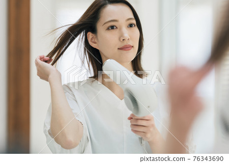 Young woman using a hairdryer in the washroom 76343690