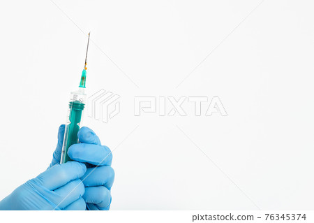 A doctor's hand in a medical glove holds a syringe with a needle to protect against the flu virus 76345374