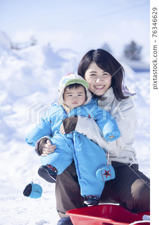 Baby and mom enjoying playing in the snow 76346629