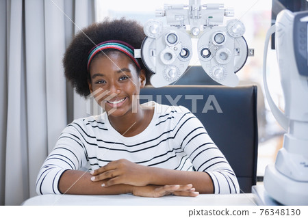Happy young woman african american eye exam with diagnostic ophthalmology in optical clinic. 76348130