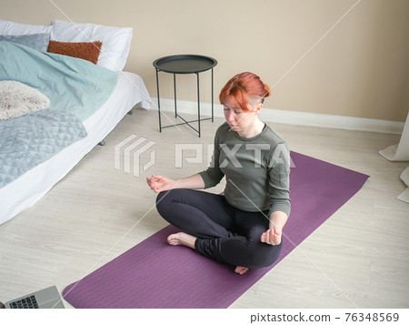 Girl meditate at home in bedroom near bed. Online Girl meditate at home in bedroom near bed. Online 76348569