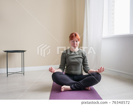 Red hair woman do meditative practice in home 76348572