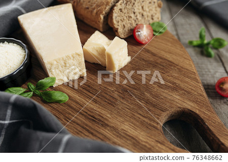 Italian cuisine concept. Grated Parmesan Cheese, chunks, tomatos, basil, bread Italian cuisine concept. Grated Parmesan Cheese, chunks, tomatos, basil, bread 76348662