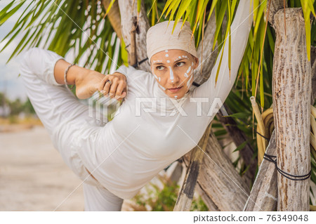 Kundalini yoga woman in white clothes and turban practices yoga kundalini on the background of the sea, mountains and sunset. Fighting face painting of the Indians shows her inner world. Visual Kundalini yoga woman in white clothes and turban practices yoga kundalini on the background of the sea, mountains and sunset. Fighting face painting of the Indians shows her inner world. Visual 76349048