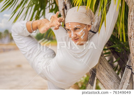 Kundalini yoga woman in white clothes and turban practices yoga kundalini on the background of the sea, mountains and sunset. Fighting face painting of the Indians shows her inner world. Visual Kundalini yoga woman in white clothes and turban practices yoga kundalini on the background of the sea, mountains and sunset. Fighting face painting of the Indians shows her inner world. Visual 76349049