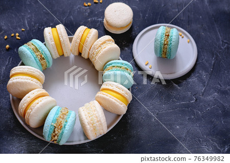 french dessert macaroons on a plate on grey background.turqiouse and beige macarons hand made. home bakery concept. sugar free baking french dessert macaroons on a plate on grey background.turqiouse and beige macarons hand made. home bakery concept. sugar free baking 76349982