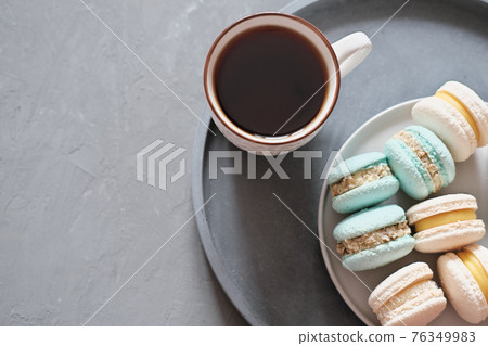 french macaroons and a cup of coffee on concrete background. home made macarons. good morning blogger content french macaroons and a cup of coffee on concrete background. home made macarons. good morning blogger content 76349983