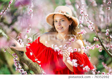 Young girl standing in spring blooming garden Young girl standing in spring blooming garden 76352092