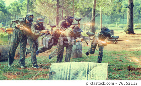 Team of adult people playing paintball on battlefield outdoor, r 76352112