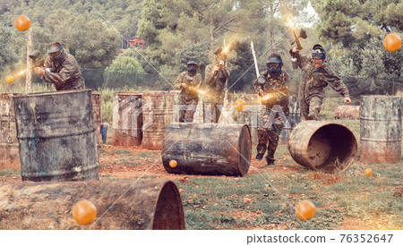 Team of adult people playing paintball on battlefield outdoor, r Team of adult people playing paintball on battlefield outdoor, r 76352647