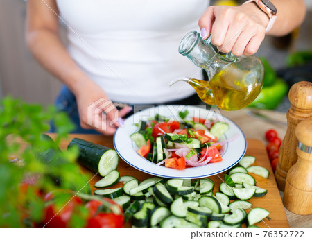 Female hands cuts vegetables on cutting board Female hands cuts vegetables on cutting board 76352722