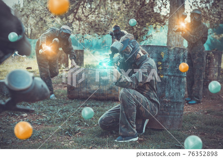 Team of adult people playing paintball on battlefield outdoor, r Team of adult people playing paintball on battlefield outdoor, r 76352898