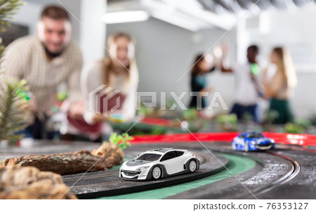 Men and women play with slot car racing track 76353127