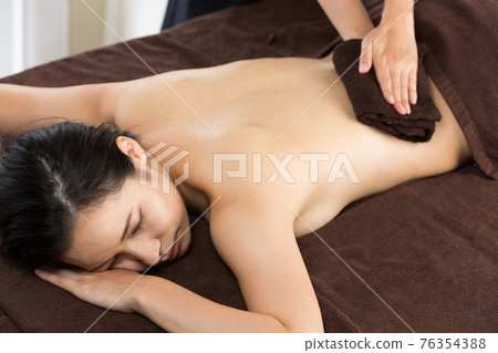 Woman wiping her back with a towel 76354388