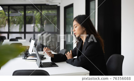 Side view of serious businesswoman working with computer tablet in modern office. 76356088