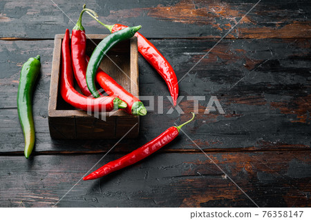 Red and green chili pepper, in wooden box, on dark wooden background , with copyspace and space for text Red and green chili pepper, in wooden box, on dark wooden background , with copyspace and space for text 76358147