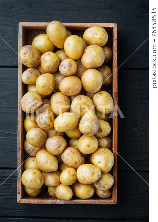 Baby potatoes small round potato from india, in wooden box, on black wooden table background, top view flat lay Baby potatoes small round potato from india, in wooden box, on black wooden table background, top view flat lay 76358515