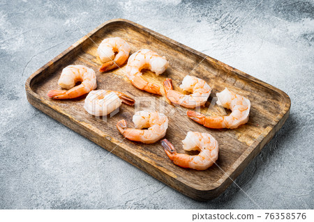 Peeled giant prawns with tails, on wooden tray, on gray background 76358576