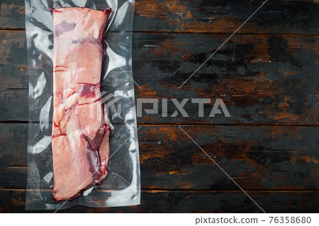 Beef short ribs in vacuum packaging, market, on old dark wooden table background, top view flat lay , with copyspace and space for text 76358680