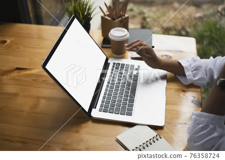 Cropped shot of female freelancer holding pencil and working on computer laptop at cafe. 76358724