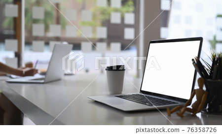 Close up view of computer laptop with blank screen on white table in meeting room. 76358726