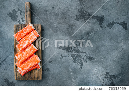 Asian snack surimi, on wooden cutting board, on gray background, top view flat lay , with copyspace and space for text Asian snack surimi, on wooden cutting board, on gray background, top view flat lay , with copyspace and space for text 76358969