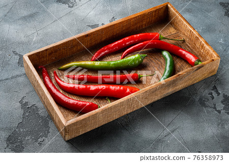Ripe Red and green chili pepper, in wooden box, on gray background Ripe Red and green chili pepper, in wooden box, on gray background 76358973