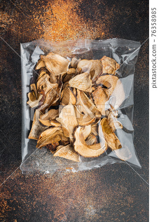 Dried porcini mushrooms, on old dark rustic background, in plastic pack, top view flat lay Dried porcini mushrooms, on old dark rustic background, in plastic pack, top view flat lay 76358985