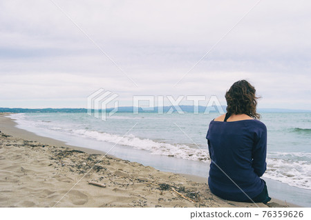 girl sitting on the sand on the shore of the beach looking at the horizon of the sea girl sitting on the sand on the shore of the beach looking at the horizon of the sea 76359626