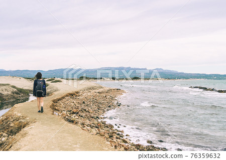 girl strolling on the shore of the beach on a cloudy day girl strolling on the shore of the beach on a cloudy day 76359632