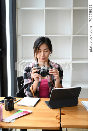 Portrait of female photographer checking pictures previews on camera. Portrait of female photographer checking pictures previews on camera. 76359931