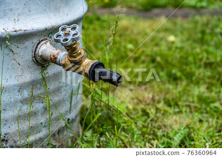 Old rusty rain barrel with water tap closeup Old rusty rain barrel with water tap closeup 76360964