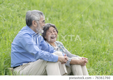 Senior couple sitting and talking outdoors Senior couple sitting and talking outdoors 76361760