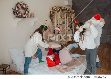 Multi-ethnic friends have fun fighting on pillows on new year's eve 76362879