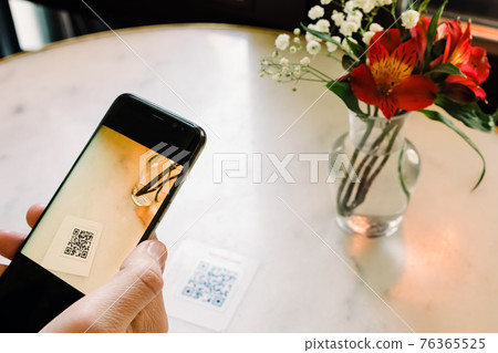 Man scanning the QR code with mobile phone at the restaurant. 76365525