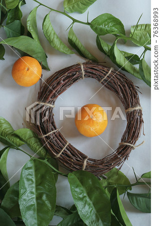 Clementines tangerines, twig with green leaves as spring decor and handmade wreath from twig on gray paper Clementines tangerines, twig with green leaves as spring decor and handmade wreath from twig on gray paper 76368993