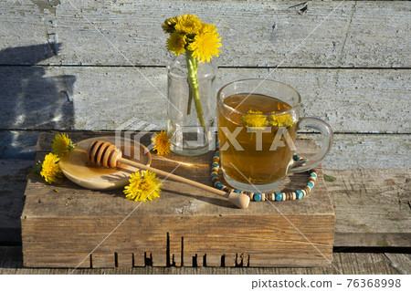 Medicinal Tea from dandelion in glass cup with honey dandelion against a blue rustic wooden wall with copy space Medicinal Tea from dandelion in glass cup with honey dandelion against a blue rustic wooden wall with copy space 76368998