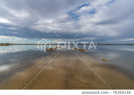 Flooded road under cloudy sky after the storm 76369188