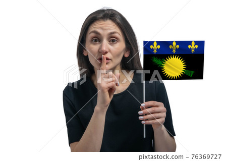 Happy young white woman holding flag of Guadeloupe and holds a finger to her lips isolated on a white background 76369727
