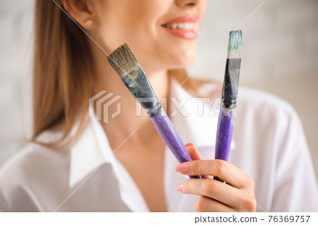 Portrait of talented young woman painting picture in art studio with inspiration. 76369757