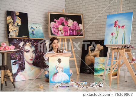 Art school student girl with her painting on exhibition show in a studio. 76369867