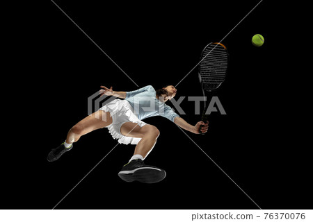 Female professional tennis player in action, motion isolated on black background, look from the bottom. Concept of sport, movement, energy and dynamic. 76370076