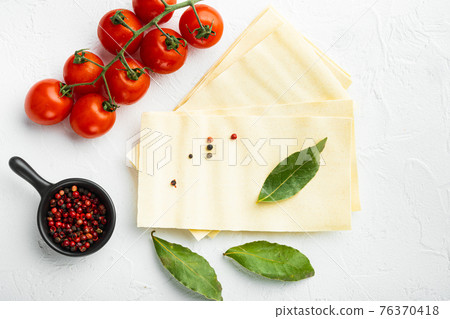 Uncooked lasagna sheets, with seasoning and herb, on white stone background, top view, flat lay 76370418