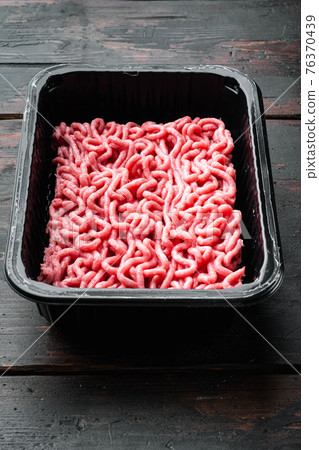 Minced meat in packaging, on old dark wooden table background 76370439