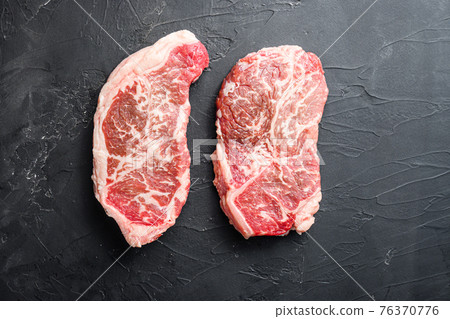 Raw top blade steak cuts, top view on black textured background with space for text Raw top blade steak cuts, top view on black textured background with space for text 76370776